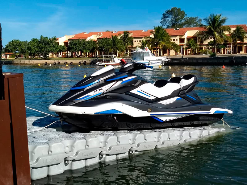 Jet Ski estacionado em um píer flutuante modular Pierplas em uma marina, com embarcações ao fundo.