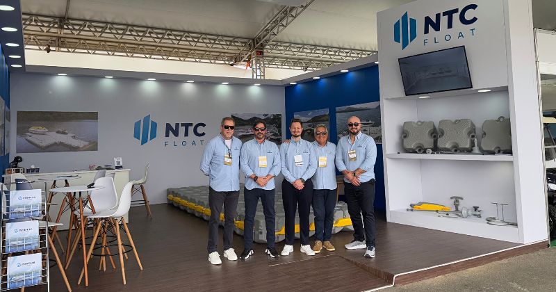 Equipe NTC em frente ao estande da Pierplas durante a Marina Itajaí Boat Show 2025. O estande apresenta soluções em plataformas flutuantes, com amostras dos produtos, material institucional e estrutura moderna para atendimento aos visitantes.