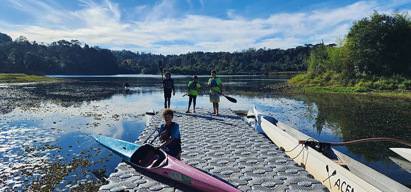 Grupo de jovens praticando canoagem, utilizando a plataforma flutuante pierplas para embarque e desembarque de caiaques.